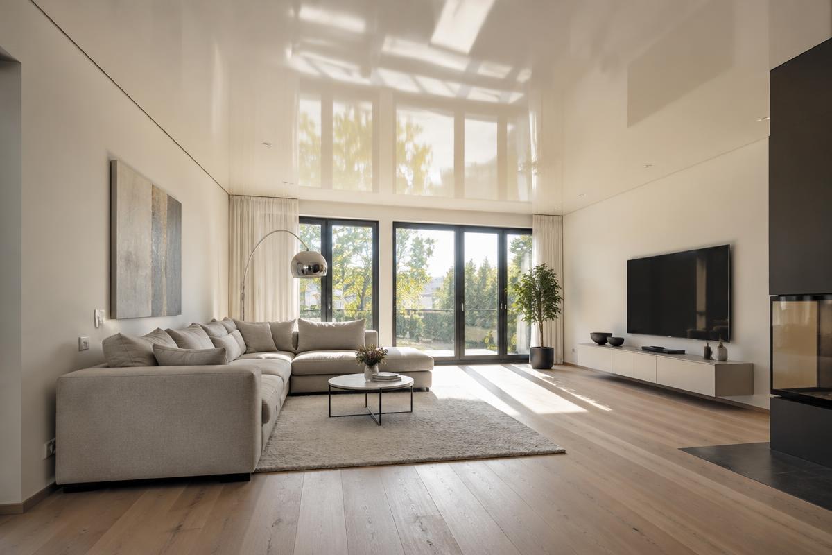 Modernes Wohnzimmer mit glänzender Spanndecke, die Tageslicht reflektiert