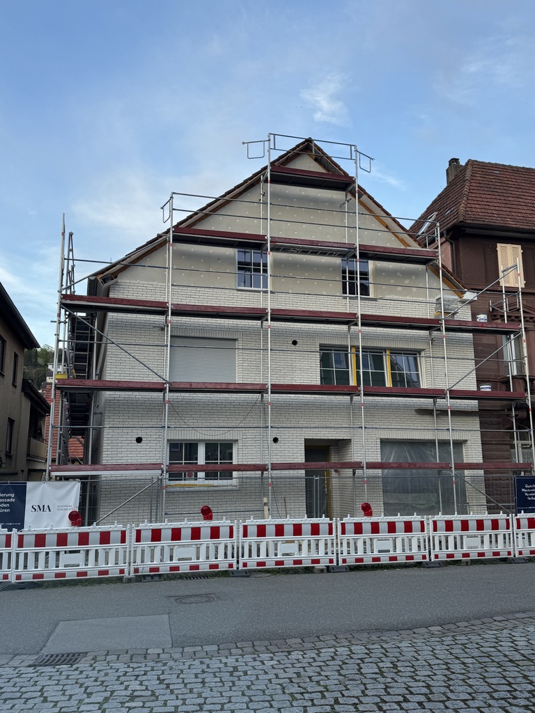 Saniertes klassisches Wohnhaus mit sauber aufgebautem Fassadengerüst vor blauem Himmel